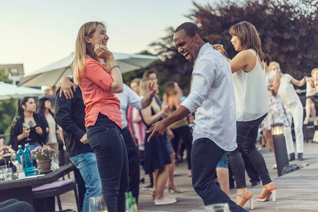 Gäste tanzen bei Tageslicht auf der Terrasse des Aspria Uhlenhorst, im Vordergrund ein Mann und zwei Frauen.