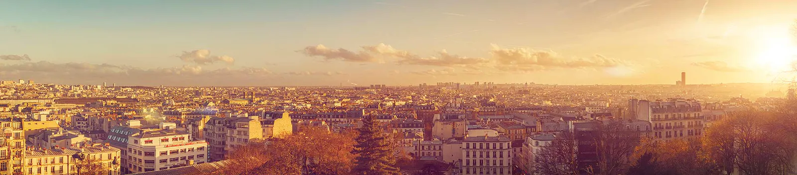 Panoramablick über dicht bebaute Dächer von Paris im goldenen Licht der tief stehenden Sonne.
