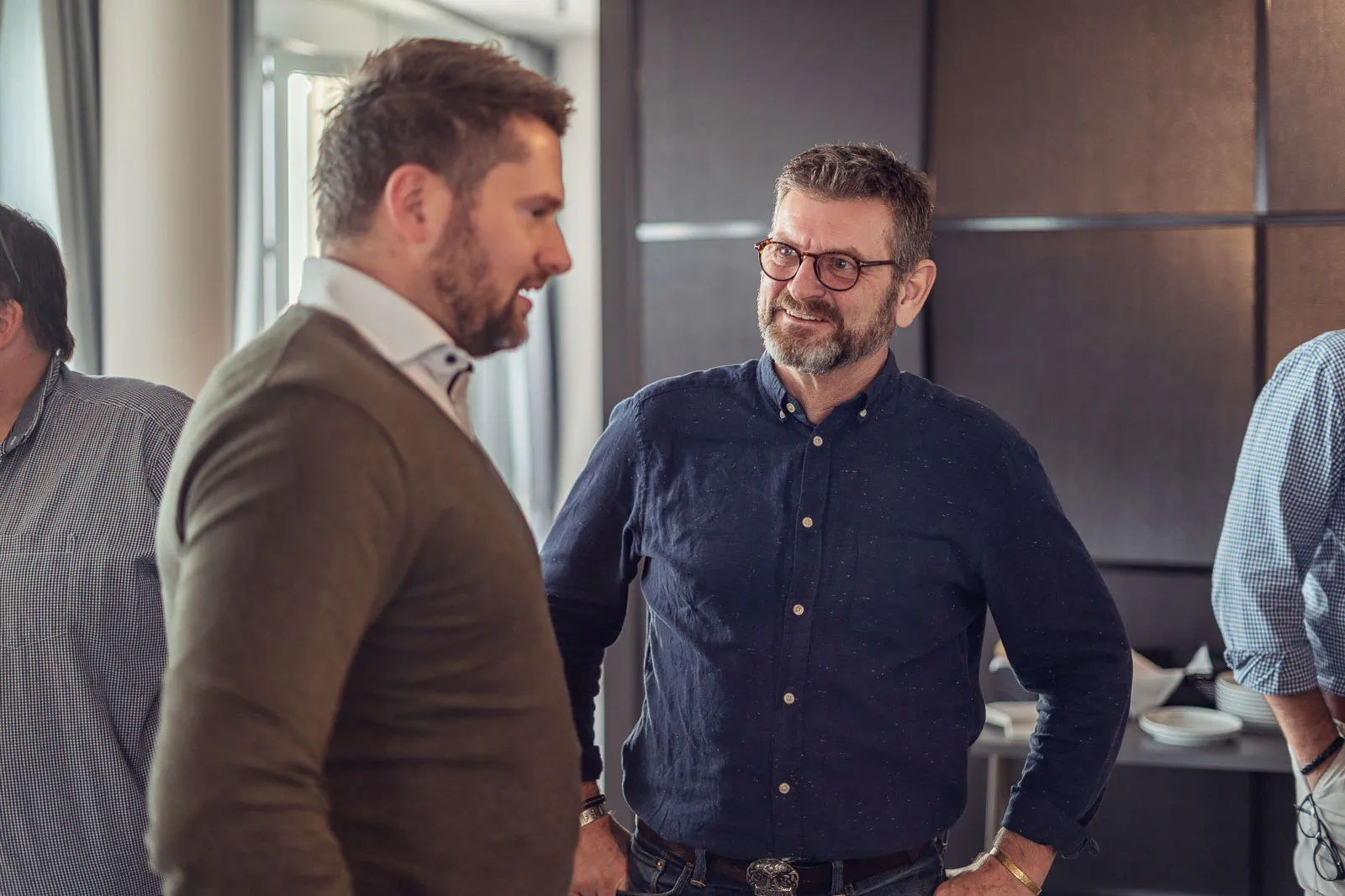 Zwei Männer im Gespräch bei einer Schüco-Veranstaltung, seitliches Tageslicht fällt durch große Fenster.