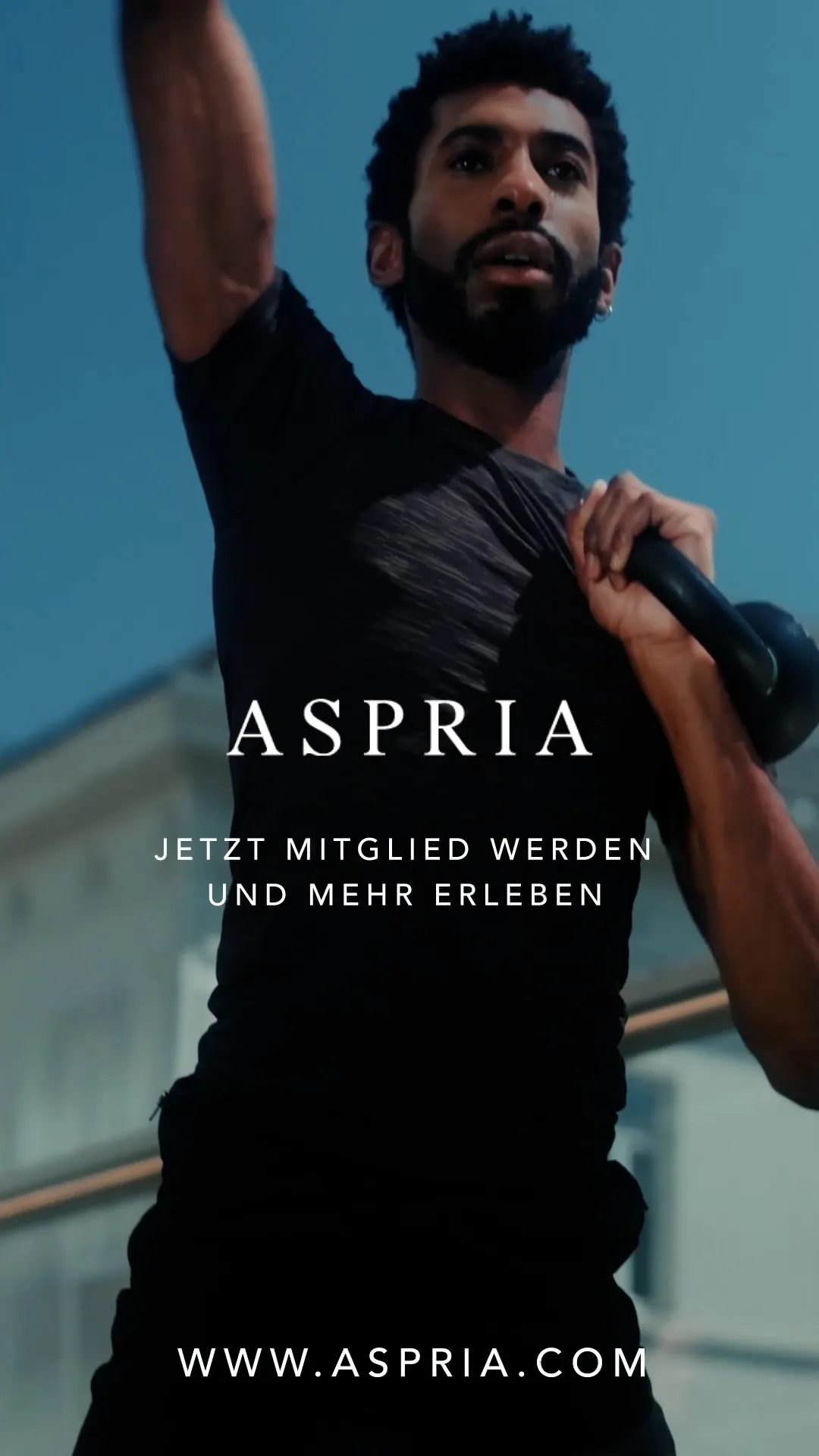 Mann im schwarzen Sportshirt hält eine Kettlebell an der Schulter und hebt einen Arm; darüber weiße Aspria-Werbung.