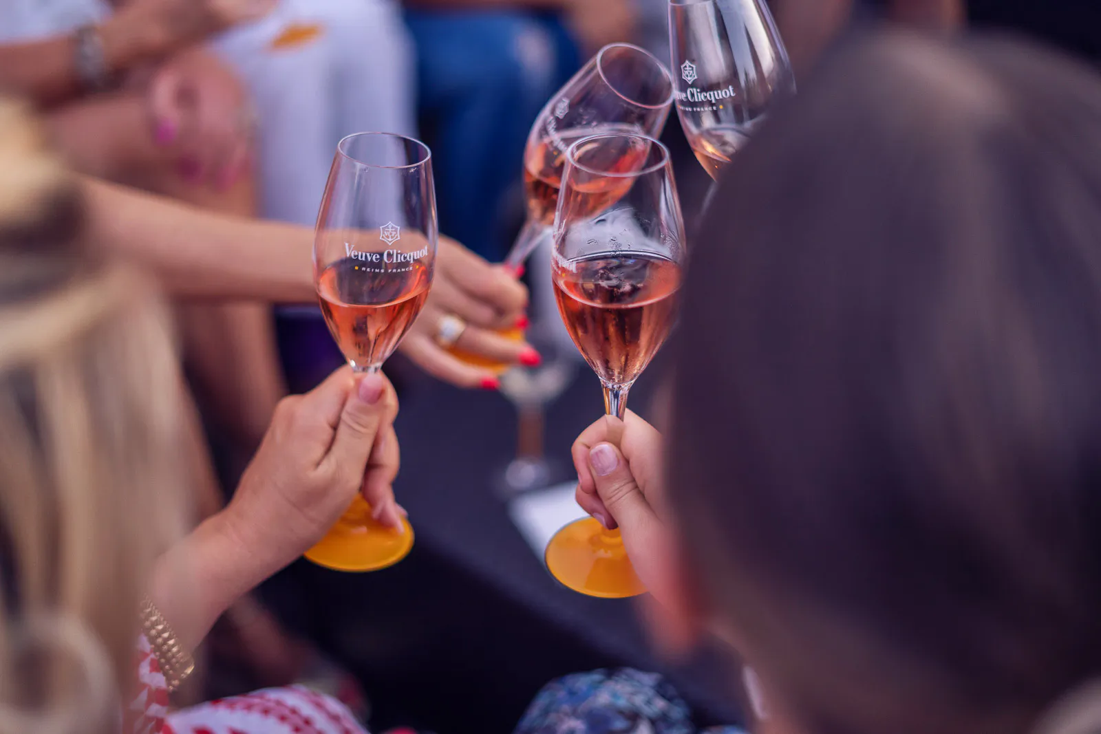 Gäste stoßen bei der Sommerparty mit Rosé-Champagner in Gläsern mit gelbem Fuß an.