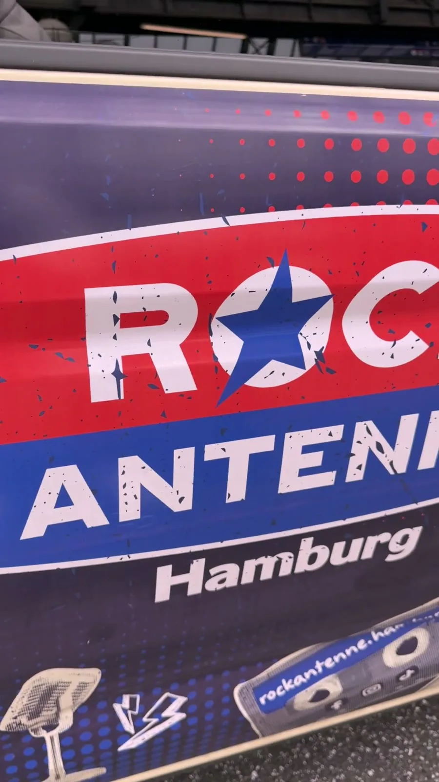 Nahaufnahme einer rot-blauen Rock-Antenne-Hamburg-Werbung an einer Fahrzeugtür mit Mikrofon- und Radioillustration.