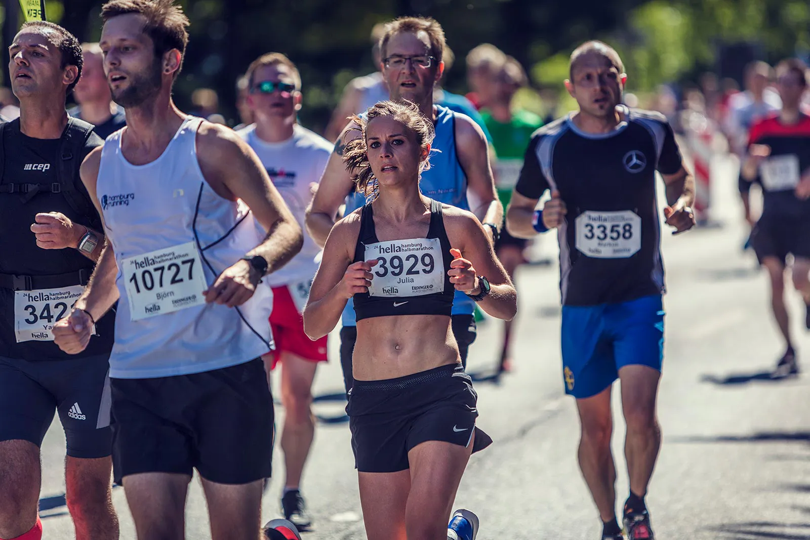 Läuferin mit Startnummer 3929 zwischen weiteren Teilnehmenden beim Hella Halbmarathon auf sonniger Straße.