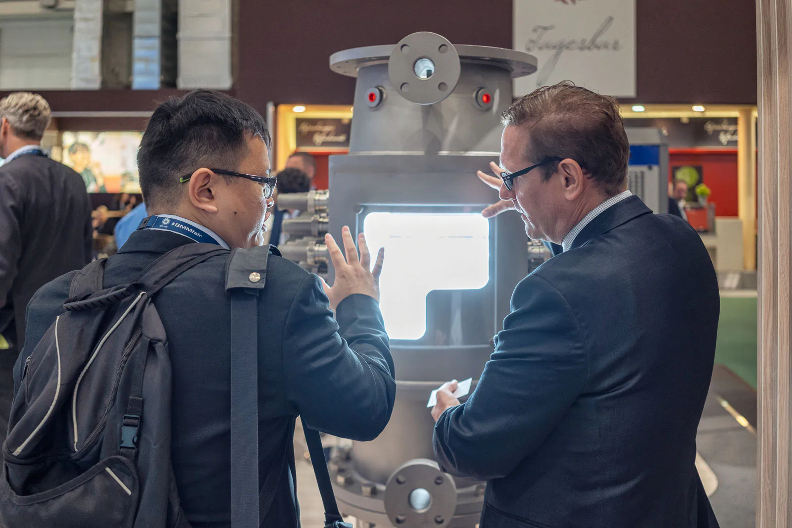 Zwei Männer im Gespräch vor einem beleuchteten Edelstahl-Exponat am Messestand von Alfa Laval.