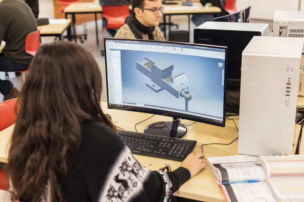 Personen im Computerraum der BS 13, vorn eine Person vor einem Bildschirm mit technischem 3D-Modell.