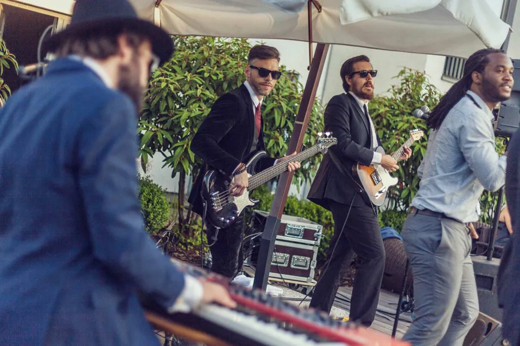 Baba Soul & the Professors of Funk spielen mit Keyboard, Bass und Gitarre draußen unter Sonnenschirmen.