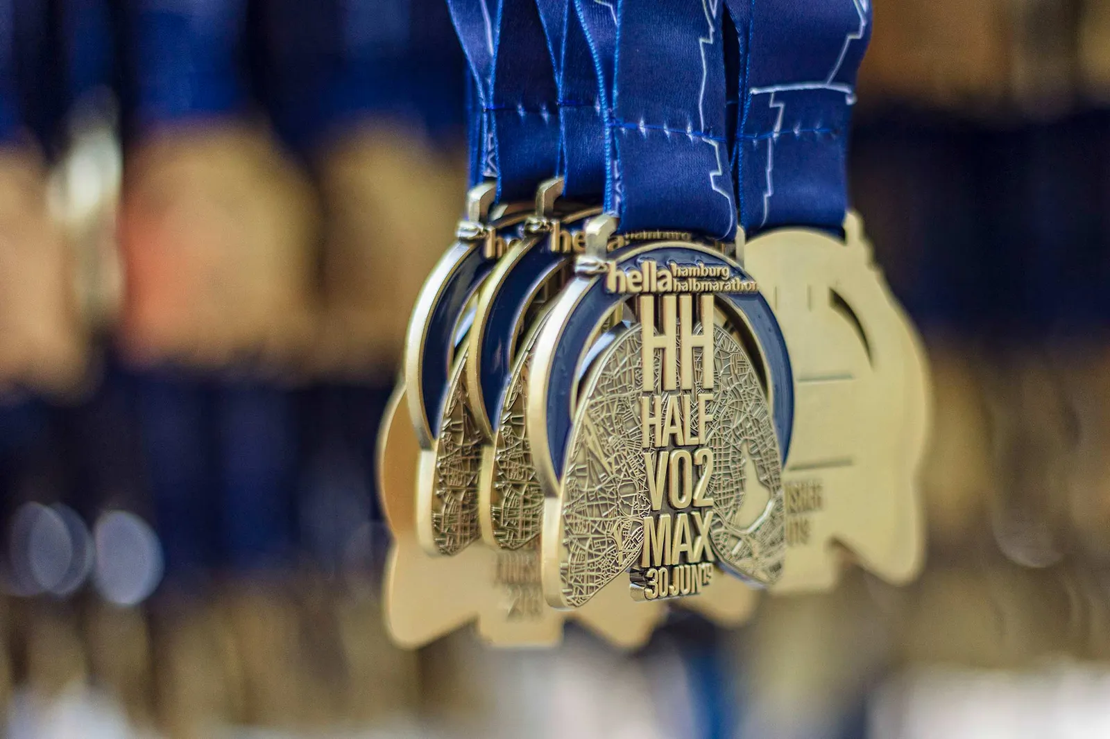 Mehrere goldfarbene Medaillen mit Halbmarathon-Prägung hängen nebeneinander an blauen Bändern.