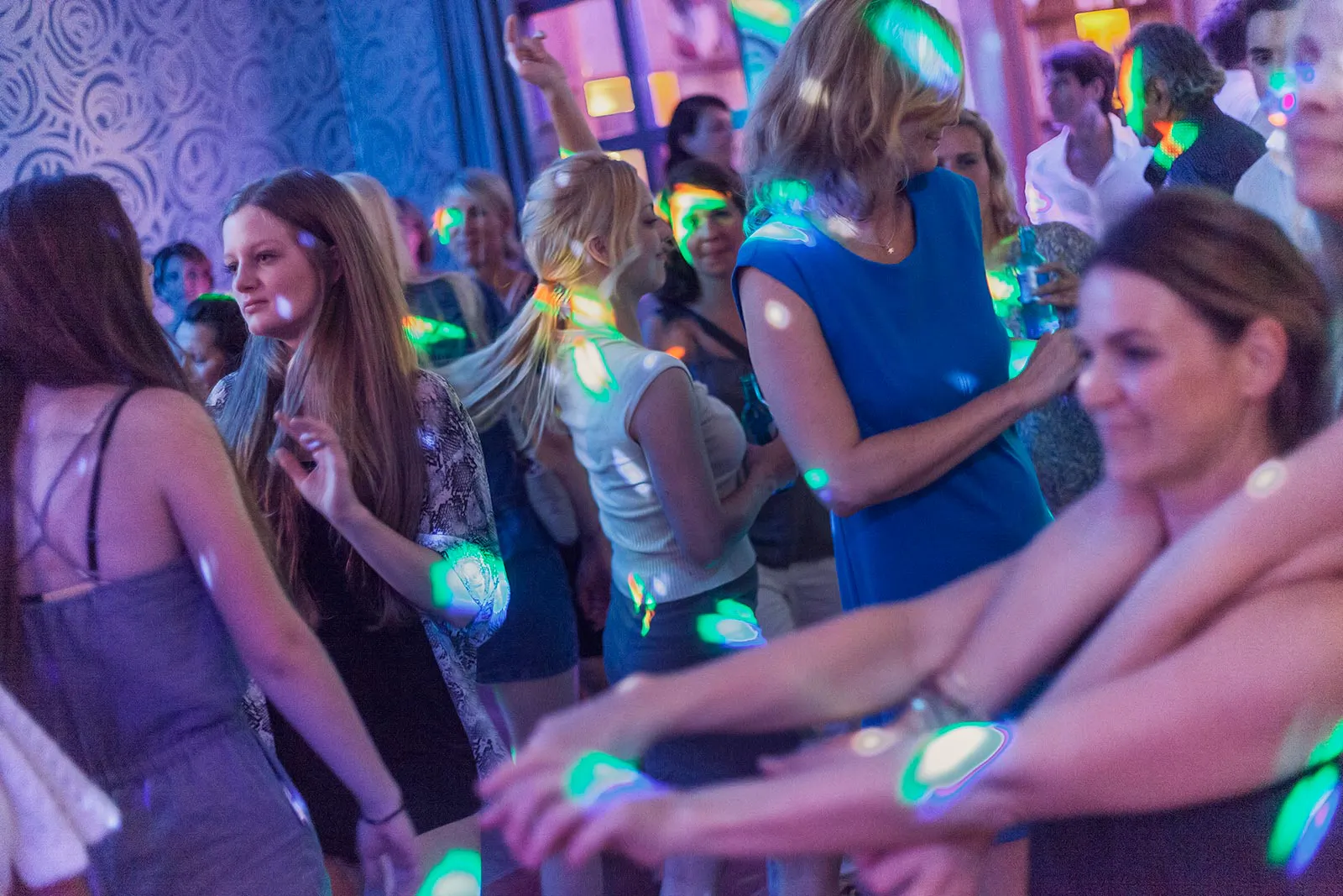 Gäste tanzen bei der Sommerparty Aspria in einem Innenraum unter bunten Partylichtern.