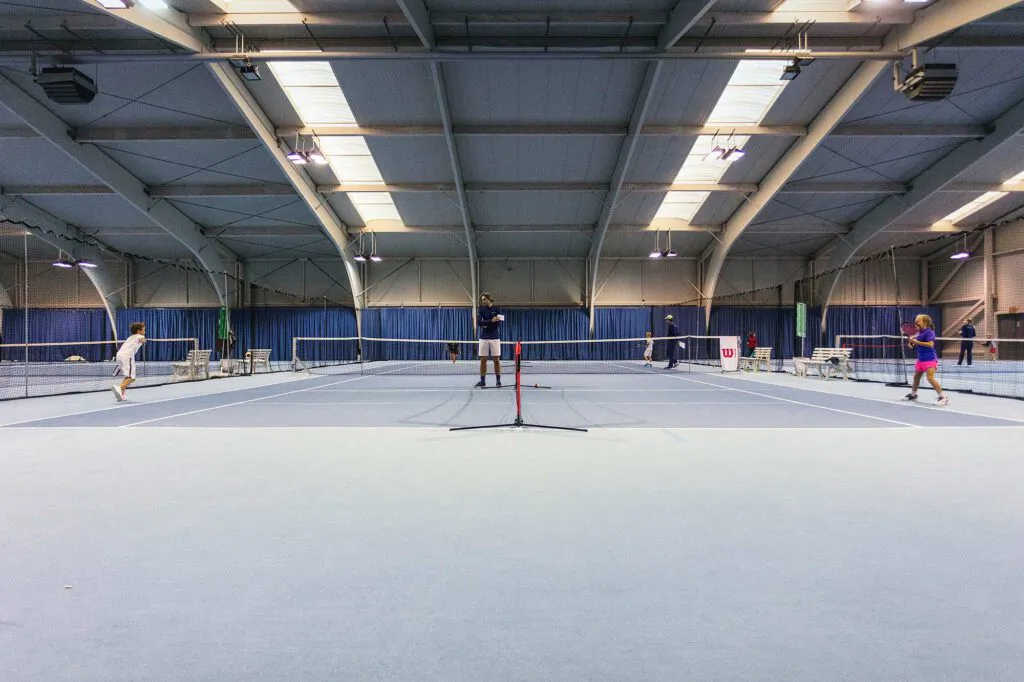 Tennisspieler auf blauen Hallenplätzen unter hellen Deckenleuchten beim Wilson Master Cup.