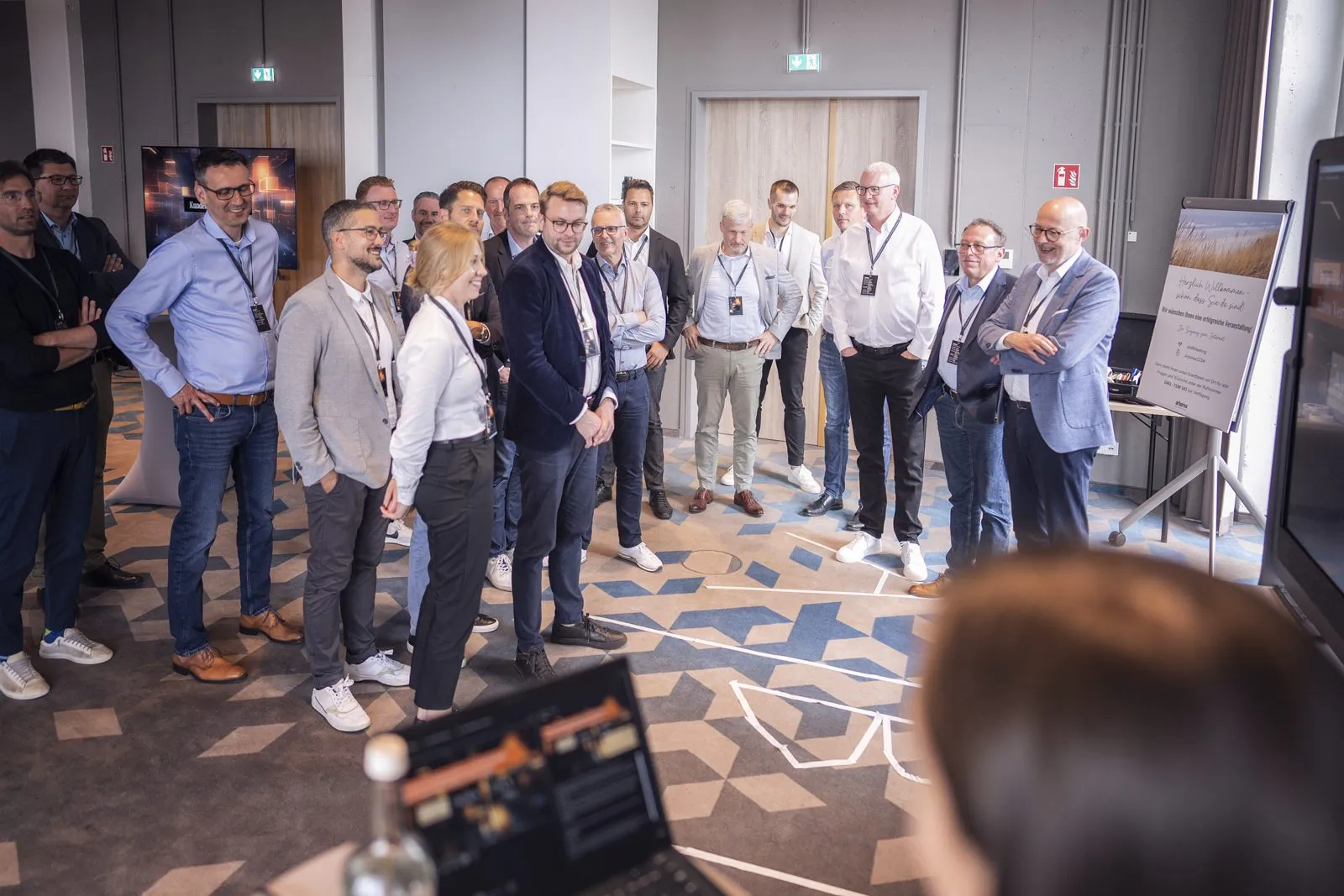 Teilnehmende mit Namensschildern stehen bei einem Mercedes-Benz-Event im hellen Tagungsraum neben einer Infotafel.