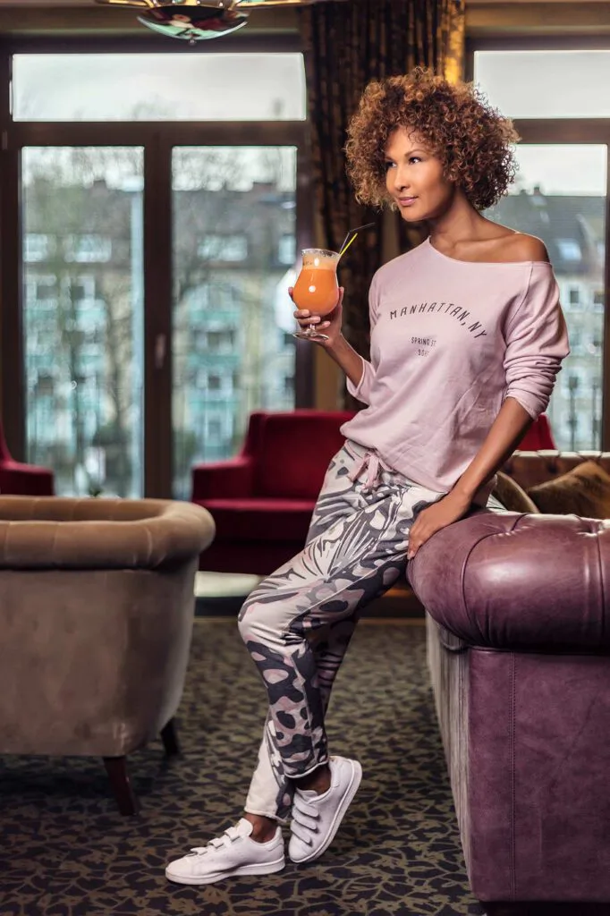 Marie Amière lehnt mit orangefarbenem Getränk an einem Ledersessel in der Lounge des Aspria Uhlenhorst.