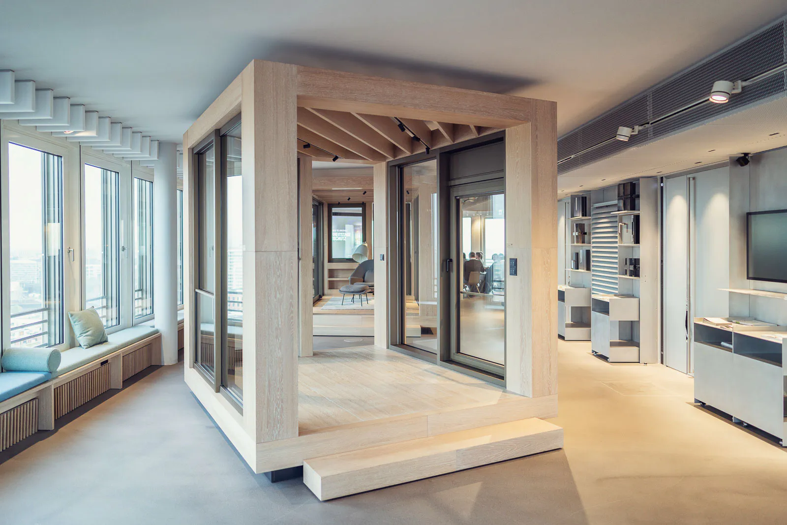 Lichtdurchfluteter Schüco-Ausstellungsraum mit Holzrahmenkonstruktion, großen Glas-Schiebetüren und Fensterfront.