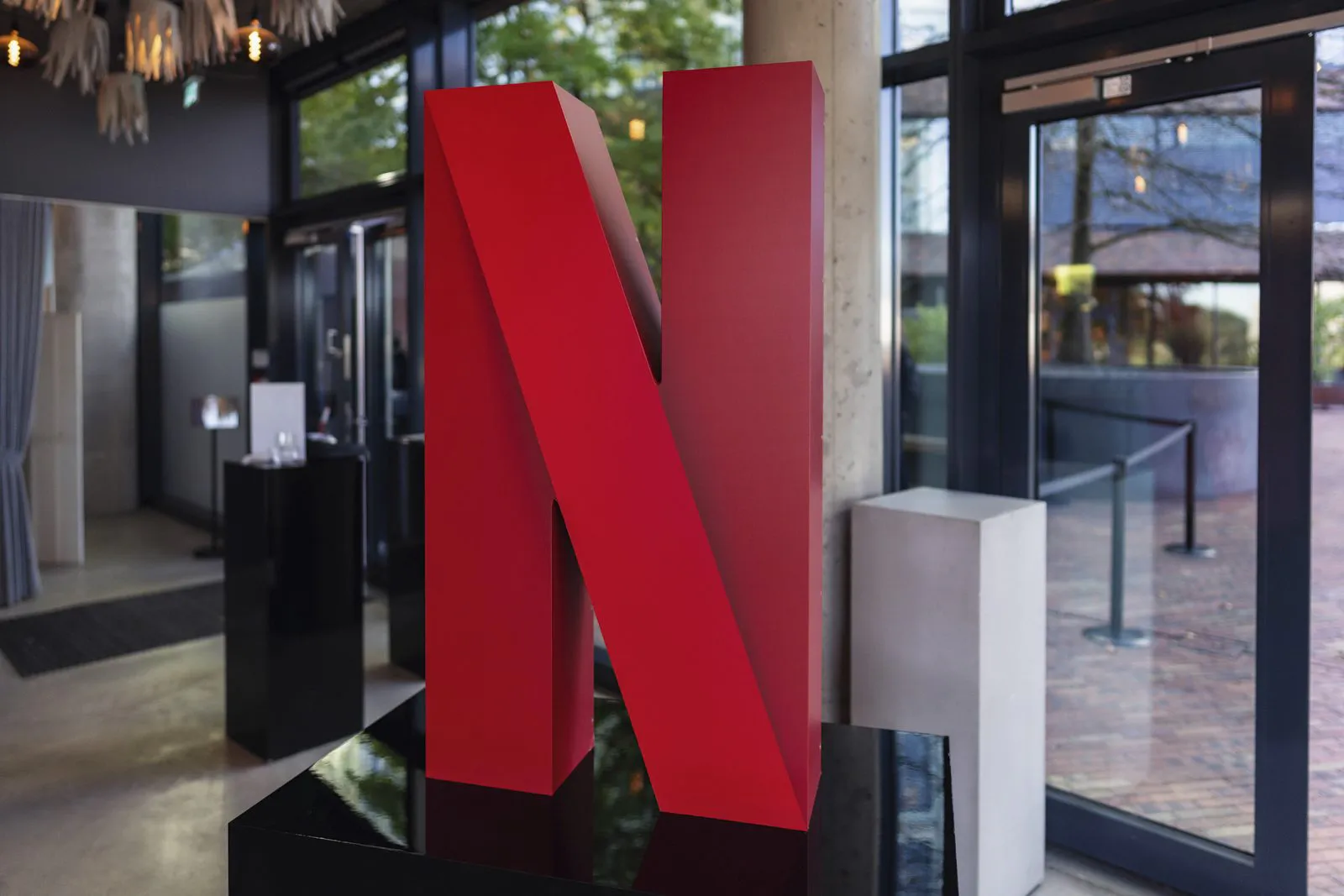 Großes rotes Netflix-N auf einem glänzenden schwarzen Sockel im verglasten Eingangsbereich einer Eventlocation.