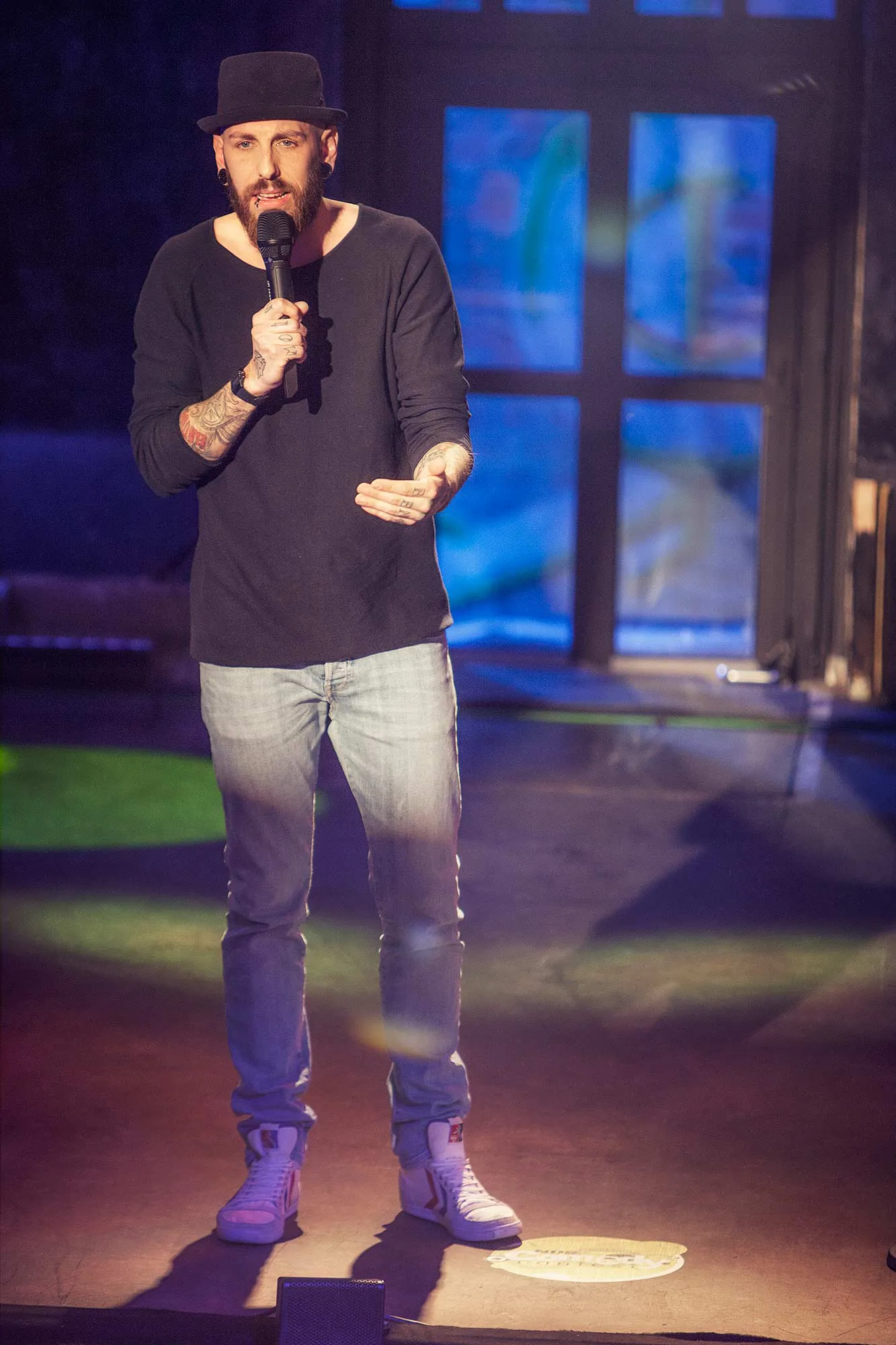 Dennis Grundt mit Mikrofon auf der Bühne beim NDR Comedy Contest, im Hintergrund blaues Licht.